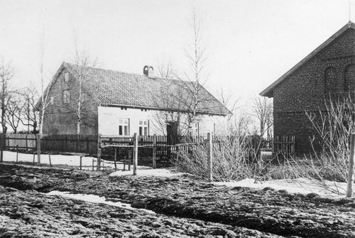 Das Soldatengrab vor dem Wohnhaus der Familie Tuttlies 1915 zunächst noch ohne Zaun innerhalb der aufgestellten Pfosten, bei genauerem Hinsehen ist aber das Kreuz erkennbar, Quelle: Foto: privat