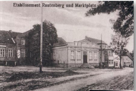 Foto: Marktplatz. Richtung Insterburg. Links der Gasthof & Kolonialwarengeschäft Rautenberg davor der Saal. Rechts Werkstatt Schwarznecker & Reck, ganz rechts das Haus von Herbert Meyer (1930) Foto: Aulenbach Ortsmitte, Quelle: Aulowöhnen – GenWiki (genealogy.net)